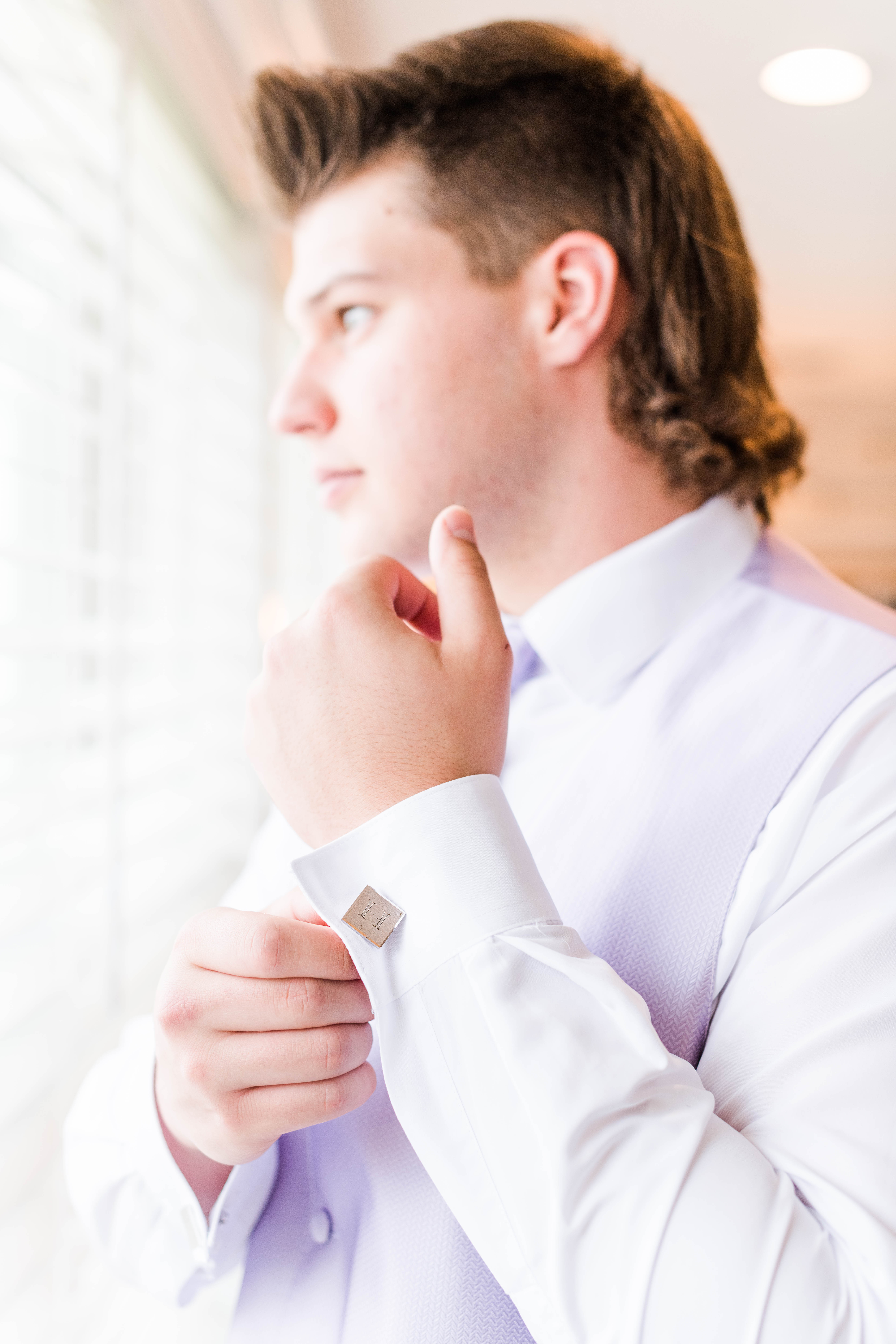 senior man adjusting his cufflink looking out the window