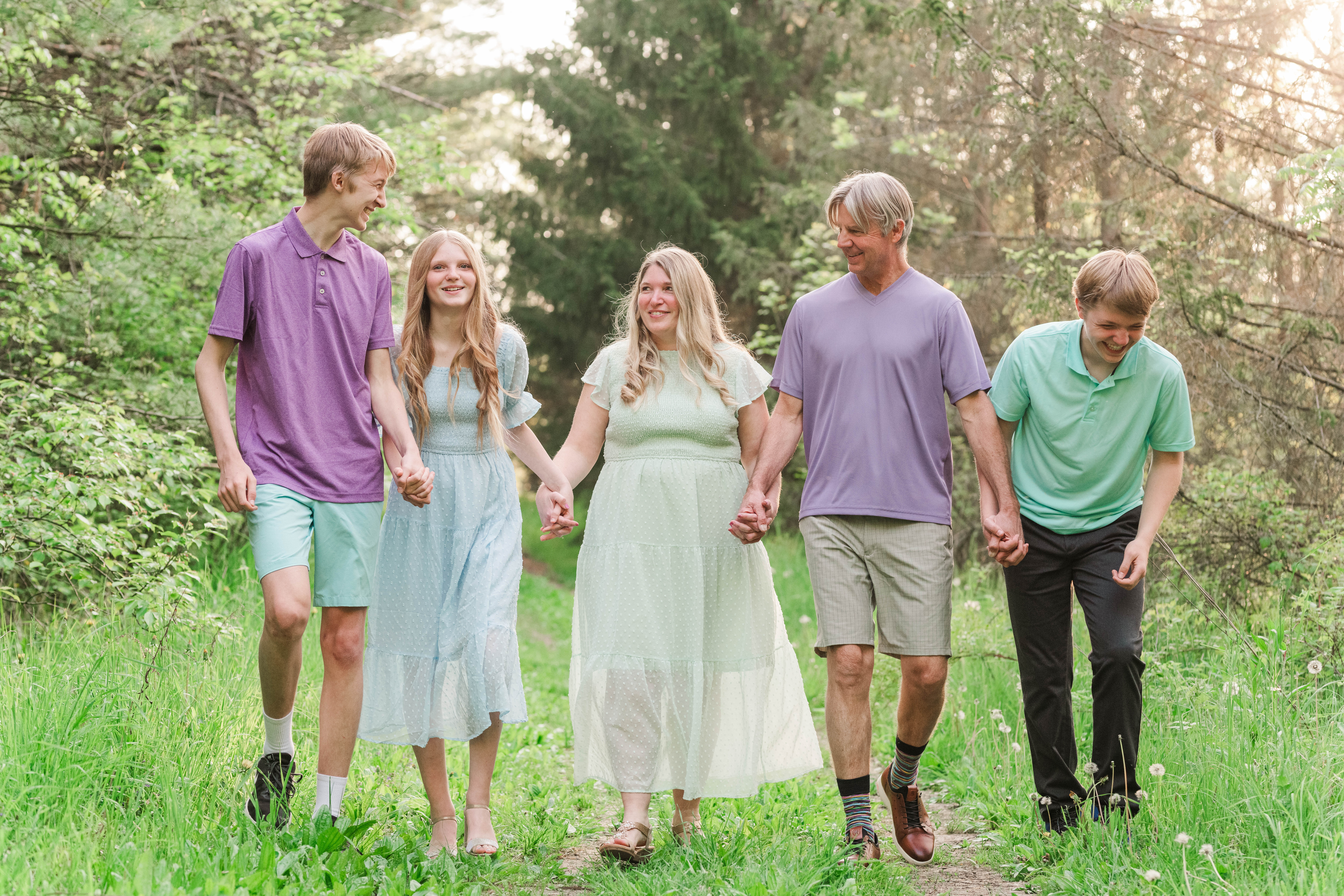 family of 5 walking hand in hand in a nature preserve