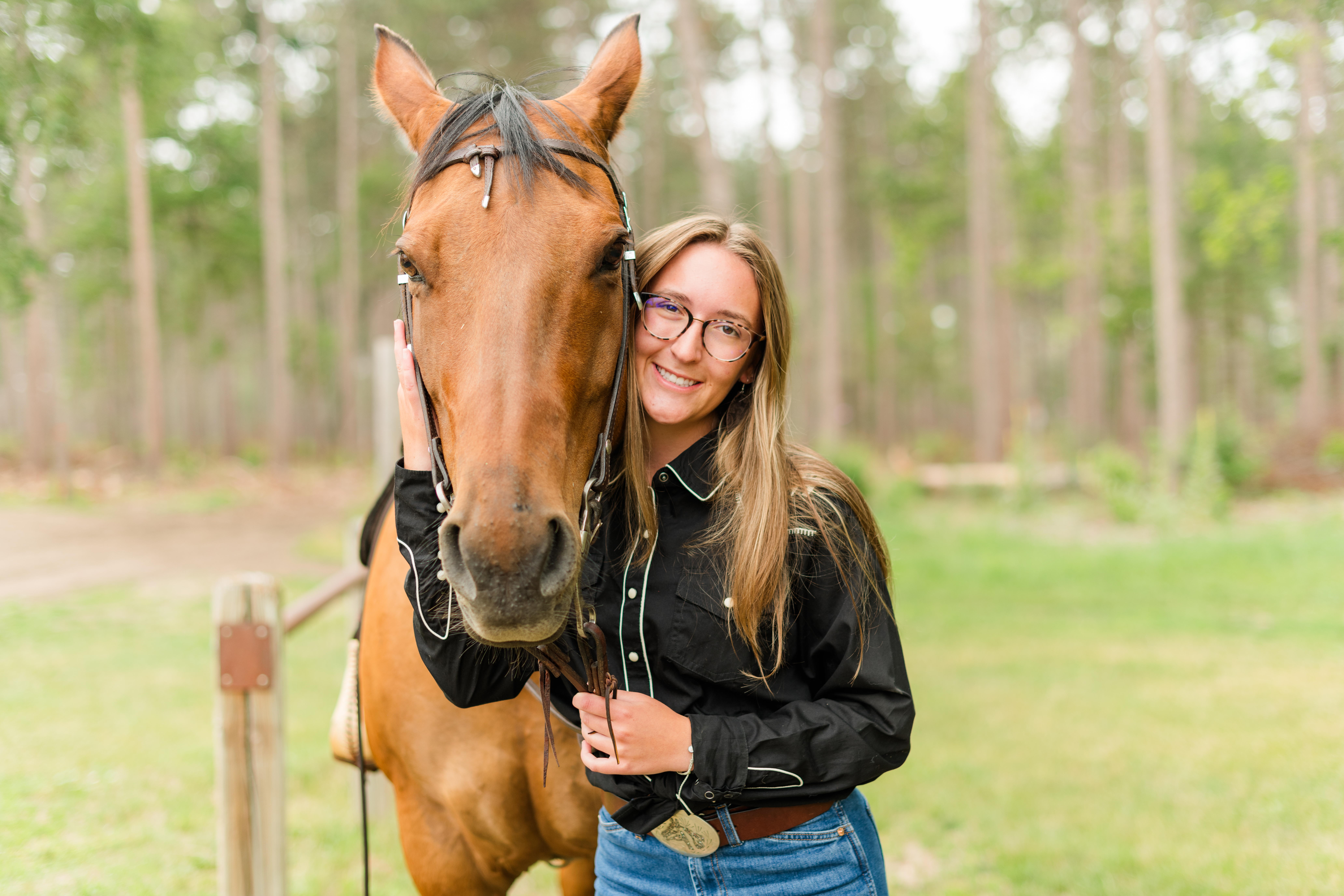 young lady smiling cupping a horses face with her hand