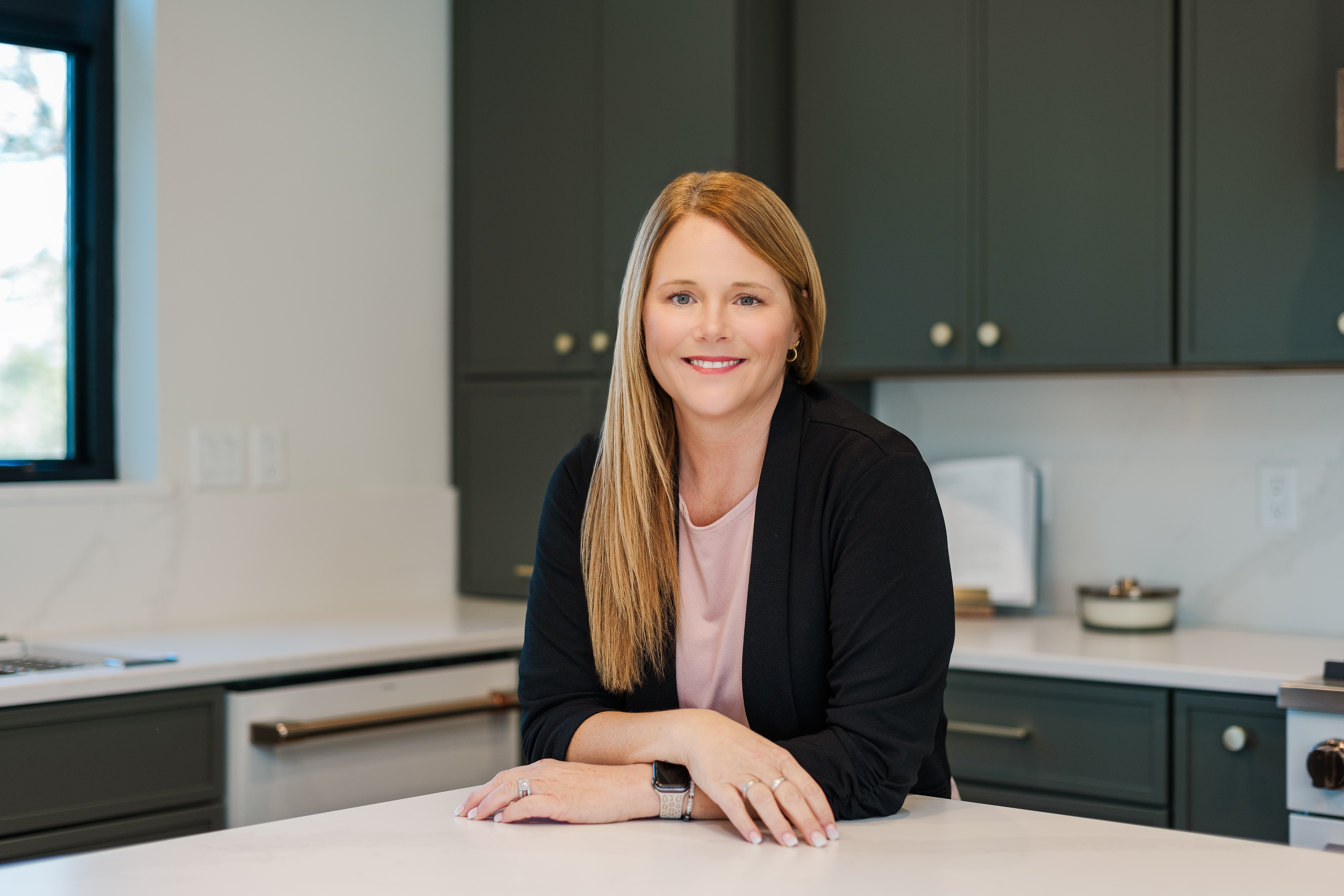 Realtor Rachel smiling softly while leaning on the kitchen counter during her branding session.